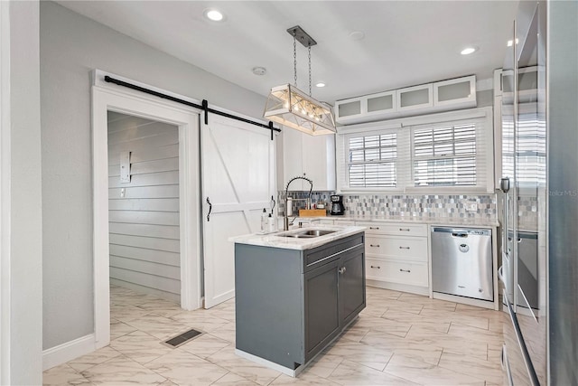 kitchen featuring pendant lighting, a barn door, white cabinetry, dishwasher, and sink