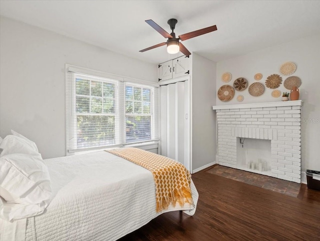 bedroom with a closet, a brick fireplace, ceiling fan, and dark hardwood / wood-style floors