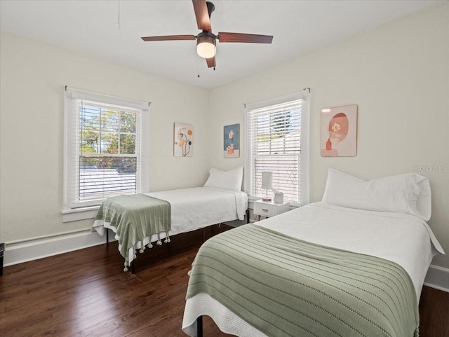 bedroom featuring ceiling fan, dark wood-type flooring, and multiple windows