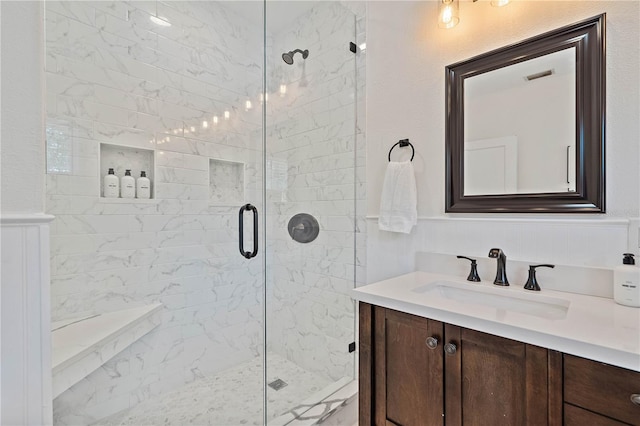 bathroom with a shower with shower door and vanity