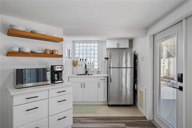 kitchen with appliances with stainless steel finishes, white cabinetry, a wealth of natural light, and sink