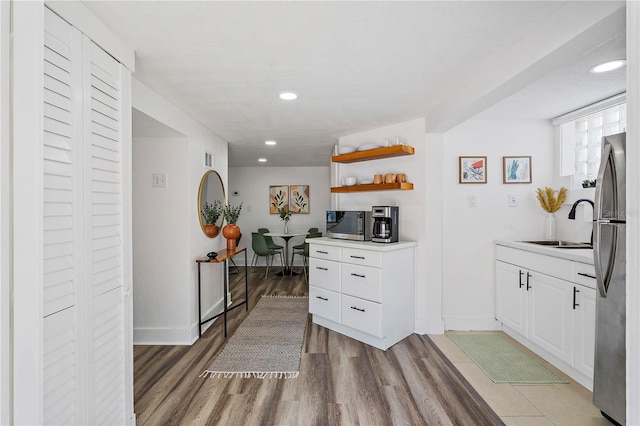 kitchen with stainless steel fridge, white cabinets, light tile floors, and sink