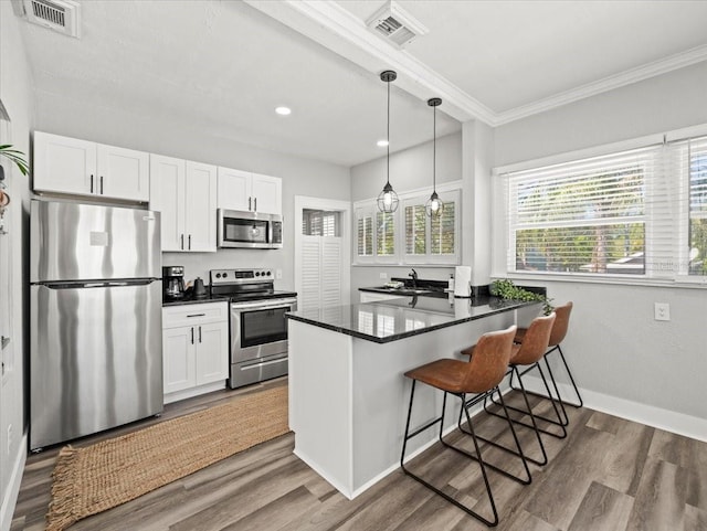 kitchen with white cabinetry, wood-type flooring, a breakfast bar area, and stainless steel appliances