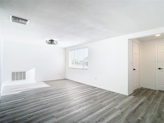 empty room with a textured ceiling and wood-type flooring