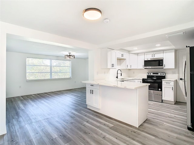 kitchen with appliances with stainless steel finishes, light hardwood / wood-style flooring, sink, kitchen peninsula, and white cabinetry