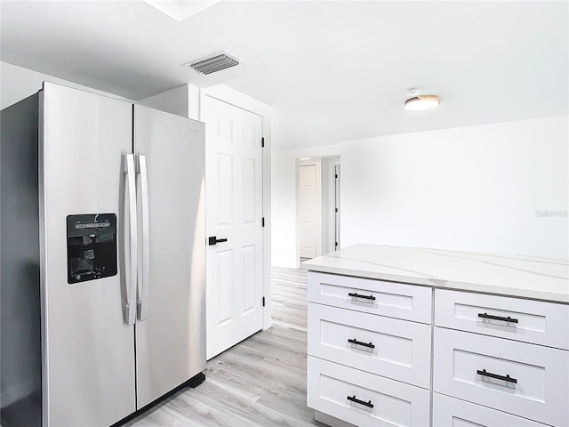 kitchen featuring white cabinets, stainless steel fridge, light stone countertops, and light hardwood / wood-style flooring