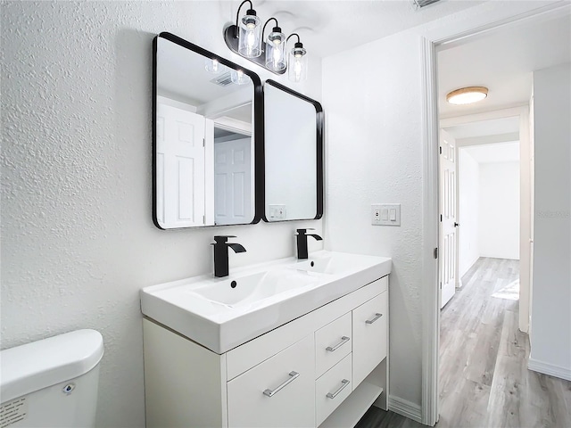 bathroom with vanity, toilet, and hardwood / wood-style floors