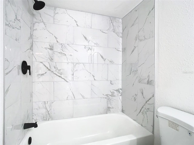 bathroom featuring toilet and tiled shower / bath