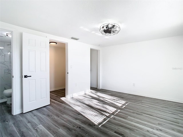 unfurnished bedroom featuring ensuite bath and dark hardwood / wood-style flooring