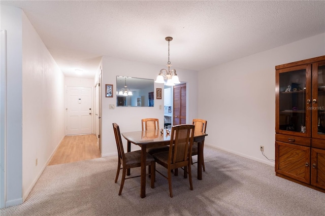 dining space with a notable chandelier, light carpet, and a textured ceiling