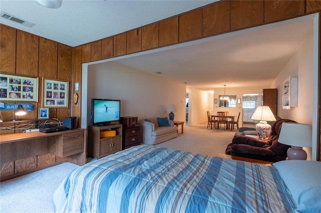 bedroom featuring a notable chandelier, light carpet, and wood walls