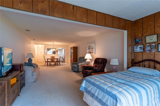 bedroom featuring a chandelier, wood walls, and light carpet