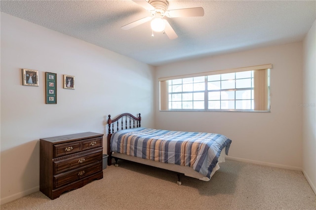 carpeted bedroom featuring ceiling fan and a textured ceiling