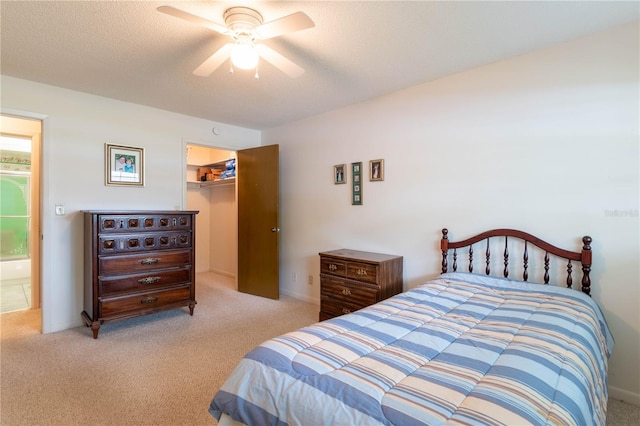 carpeted bedroom featuring a textured ceiling, a closet, ceiling fan, and a walk in closet