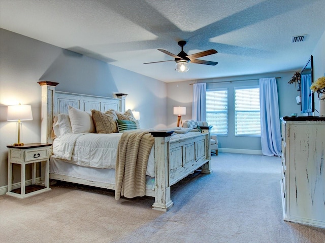 bedroom featuring ceiling fan, light carpet, and a textured ceiling