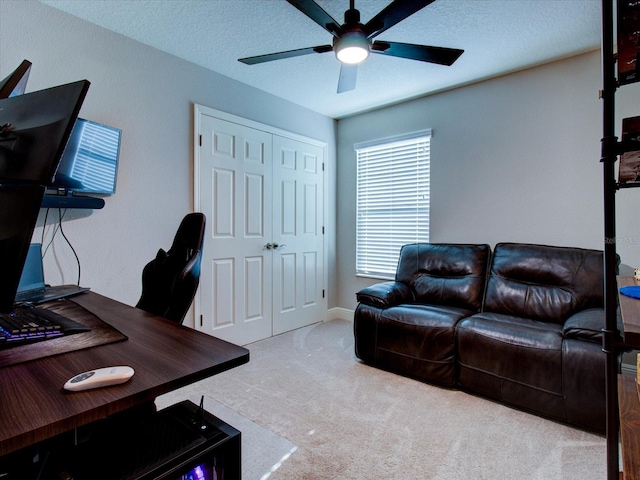 home office featuring ceiling fan, light colored carpet, and a textured ceiling