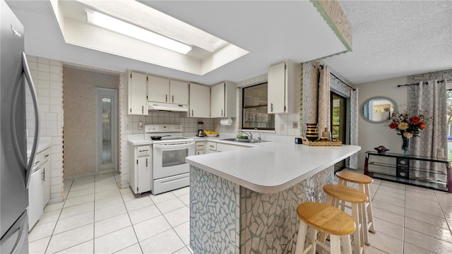 kitchen with a kitchen breakfast bar, a wealth of natural light, tasteful backsplash, and white electric range