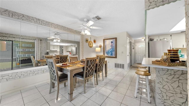 tiled dining area featuring a textured ceiling and ceiling fan