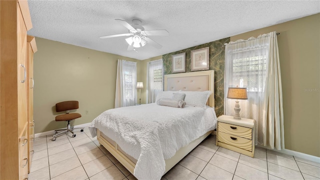 bedroom with ceiling fan, light tile floors, and a textured ceiling