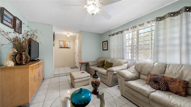 living room featuring ceiling fan, light tile floors, and a textured ceiling