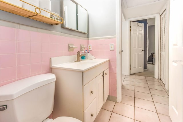 bathroom featuring vanity, toilet, tile patterned floors, and tile walls