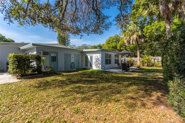 rear view of property featuring a patio and a lawn