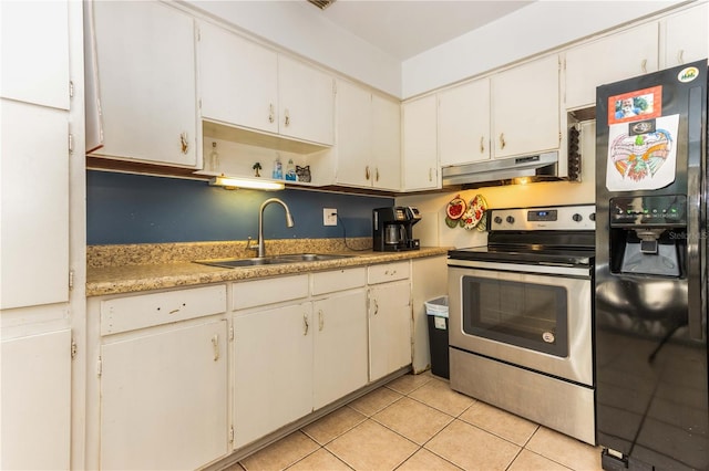 kitchen with black fridge, stainless steel range with electric stovetop, sink, light tile patterned flooring, and white cabinets