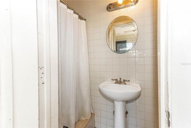 bathroom featuring curtained shower and tile walls