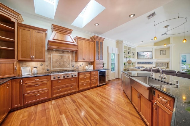 kitchen featuring dark stone counters, stainless steel gas stovetop, wine cooler, light hardwood / wood-style flooring, and custom range hood