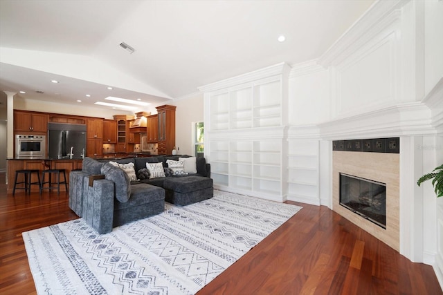 living room with lofted ceiling, ornamental molding, dark wood-type flooring, and built in features