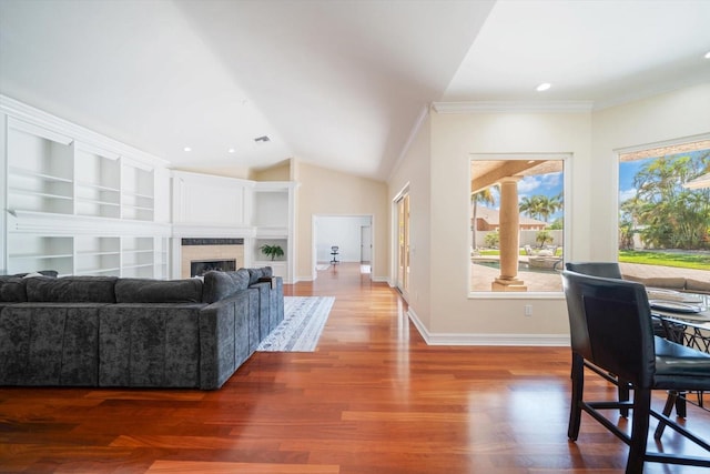 living room with crown molding, built in features, vaulted ceiling, and light hardwood / wood-style flooring