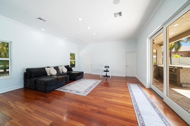 living room with a wealth of natural light, hardwood / wood-style flooring, and ornamental molding