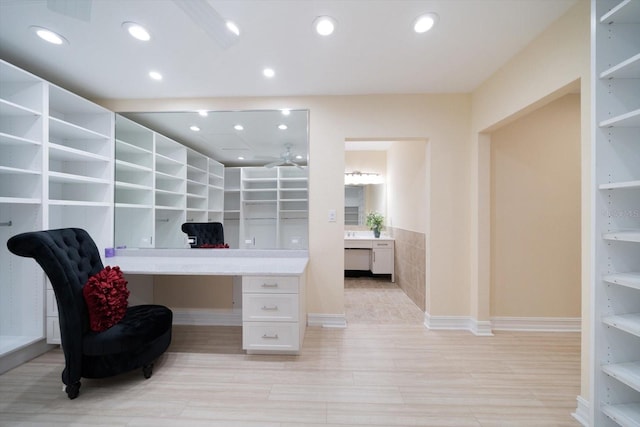 office area featuring light wood-type flooring, ceiling fan, and built in desk