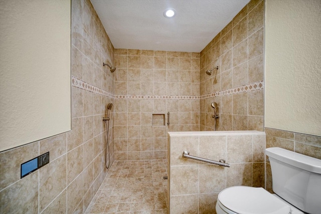 bathroom featuring tile walls, toilet, a textured ceiling, and tiled shower