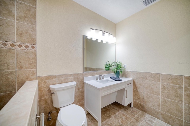 bathroom with tile walls, vanity with extensive cabinet space, tile floors, and toilet