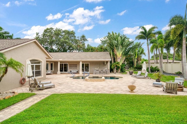 rear view of house featuring a lawn, a pool with hot tub, and a patio