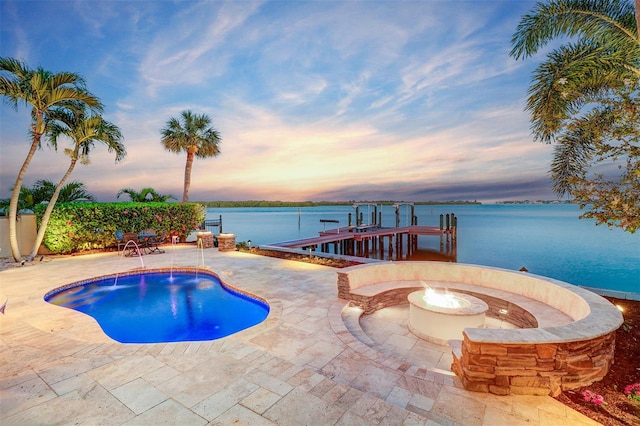 pool at dusk featuring a patio area, a fire pit, a dock, and a water view