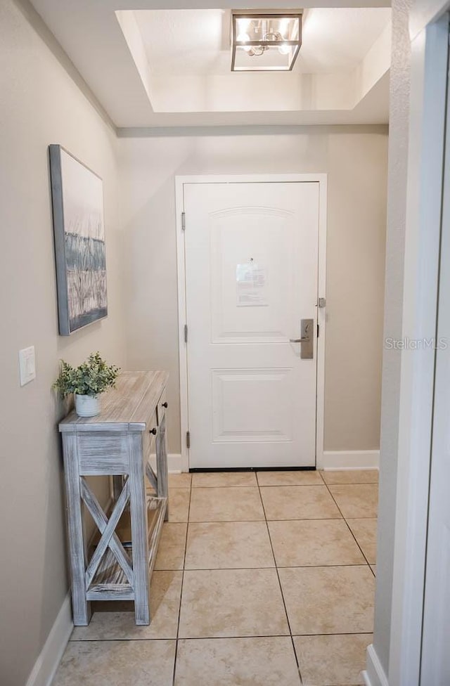 entryway with a raised ceiling and light tile patterned floors