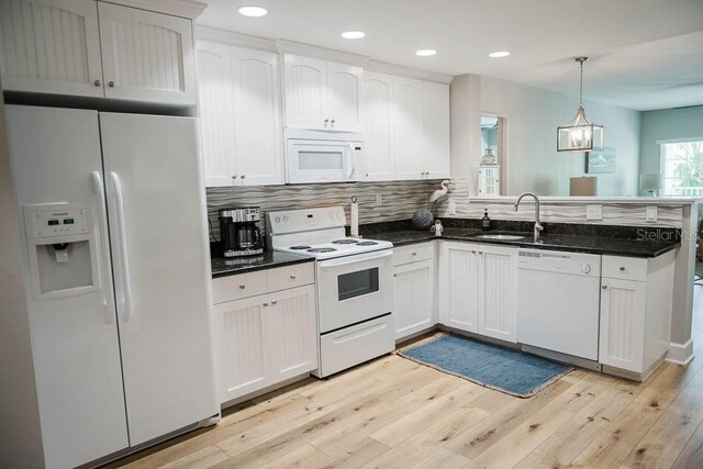 kitchen with hanging light fixtures, white appliances, and white cabinets