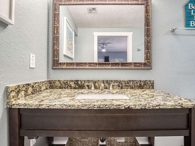 bathroom with a textured ceiling, vanity, and ceiling fan