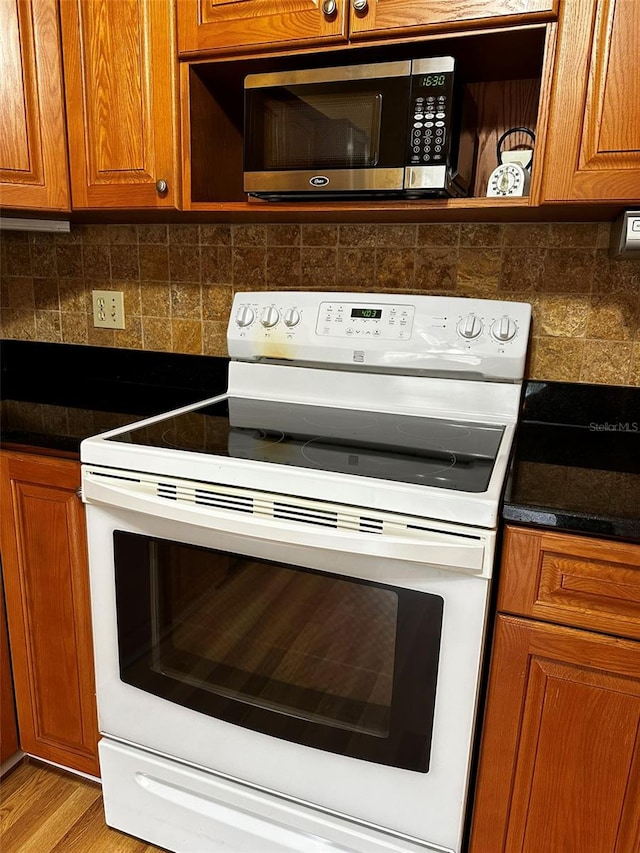 kitchen featuring white range with electric stovetop, tasteful backsplash, and light wood-type flooring