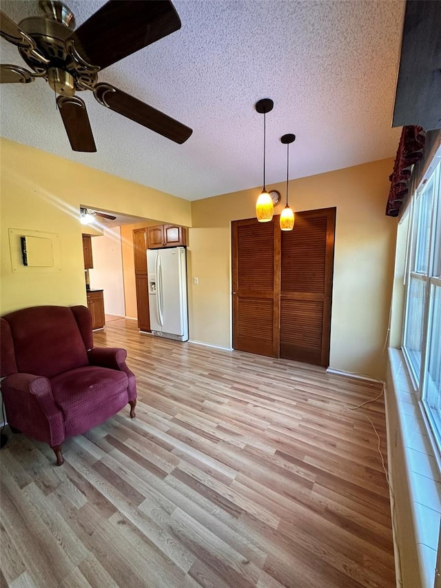 living room featuring ceiling fan, light hardwood / wood-style floors, and a textured ceiling