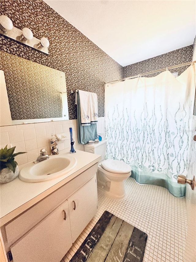 bathroom with tile patterned flooring, vanity, toilet, and tile walls