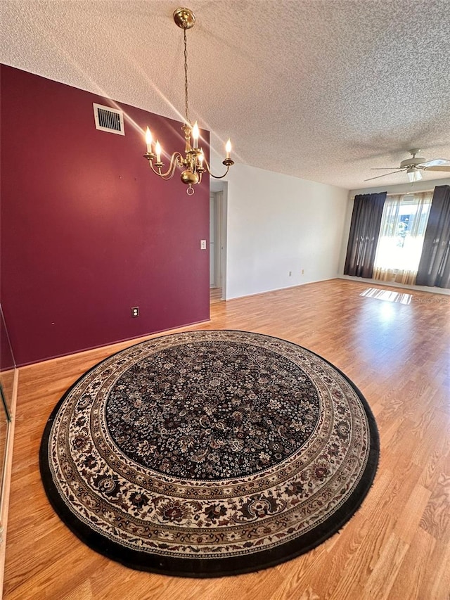 dining area featuring hardwood / wood-style floors, ceiling fan with notable chandelier, and a textured ceiling