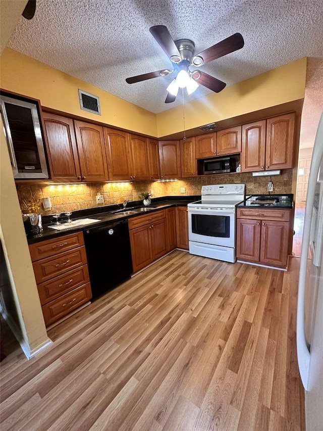 kitchen with ceiling fan, backsplash, light hardwood / wood-style floors, a textured ceiling, and white appliances