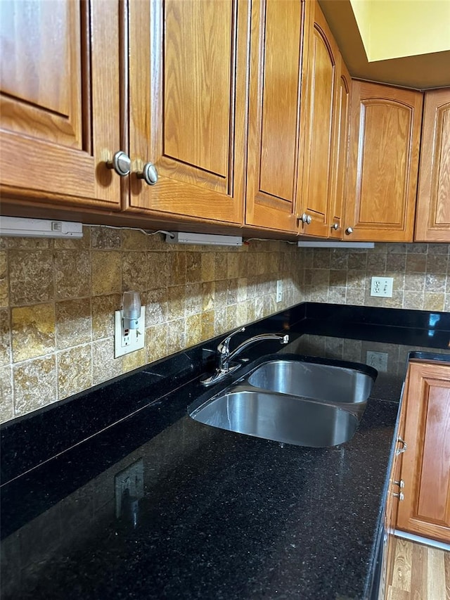 kitchen with backsplash, dark stone countertops, sink, and hardwood / wood-style floors