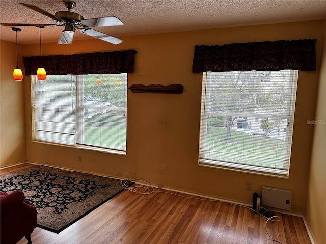 interior space featuring a wealth of natural light, hardwood / wood-style floors, ceiling fan, and a textured ceiling