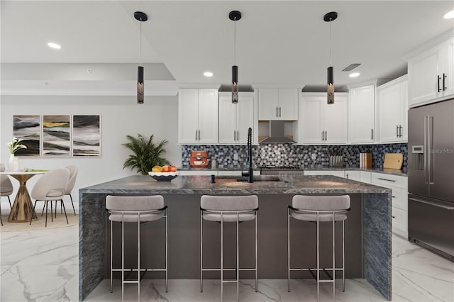 kitchen featuring wall chimney exhaust hood, pendant lighting, high end refrigerator, and light tile flooring