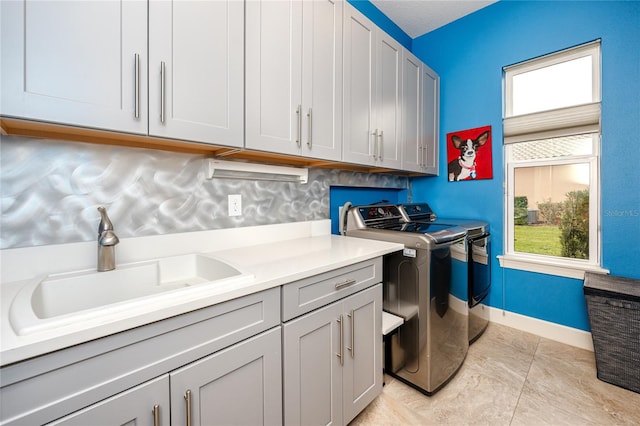 laundry room featuring light tile patterned floors, cabinets, washer and clothes dryer, and sink