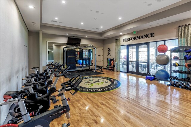 gym featuring a raised ceiling and hardwood / wood-style flooring